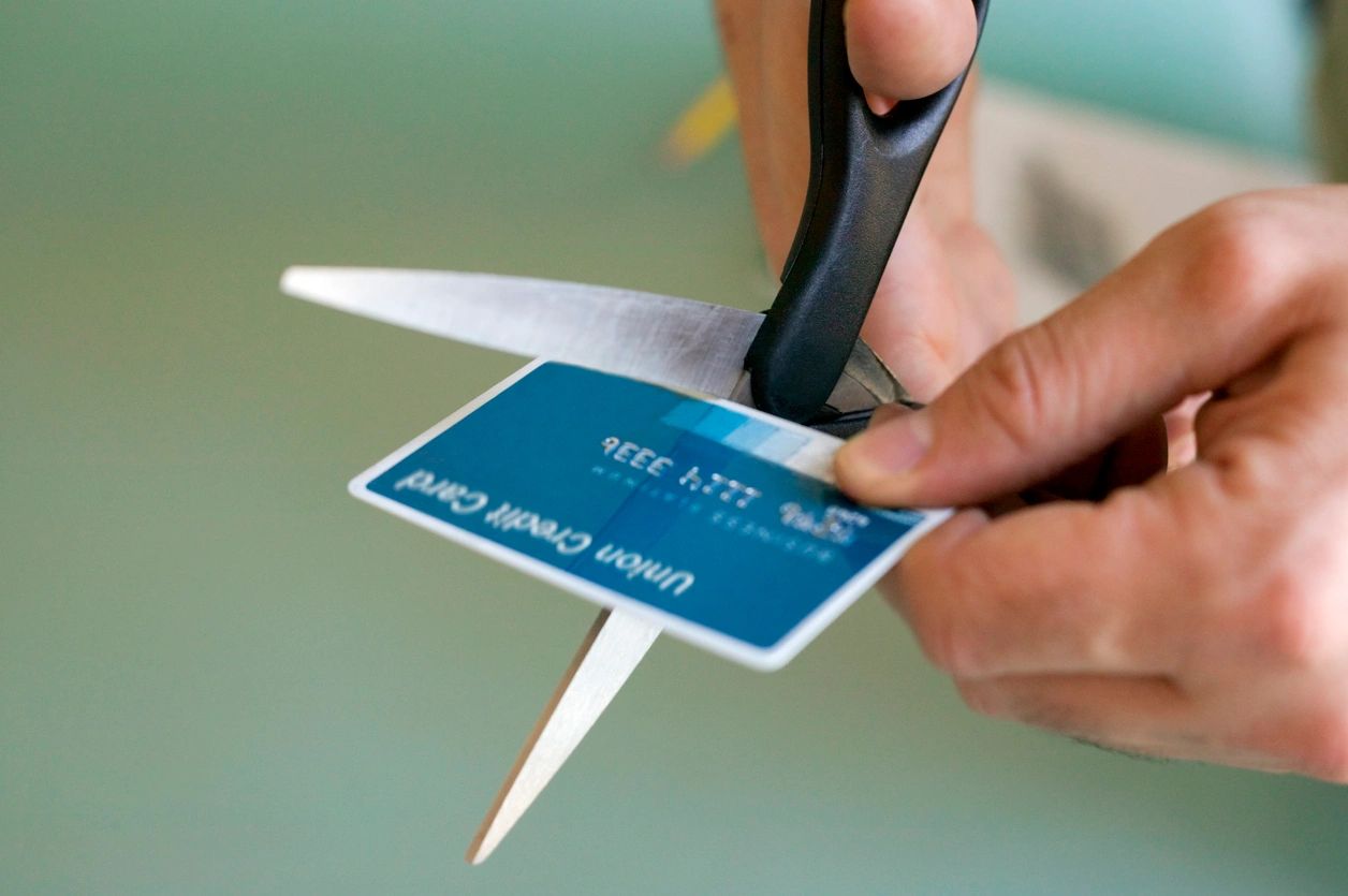 A person cutting up a credit card with scissors.