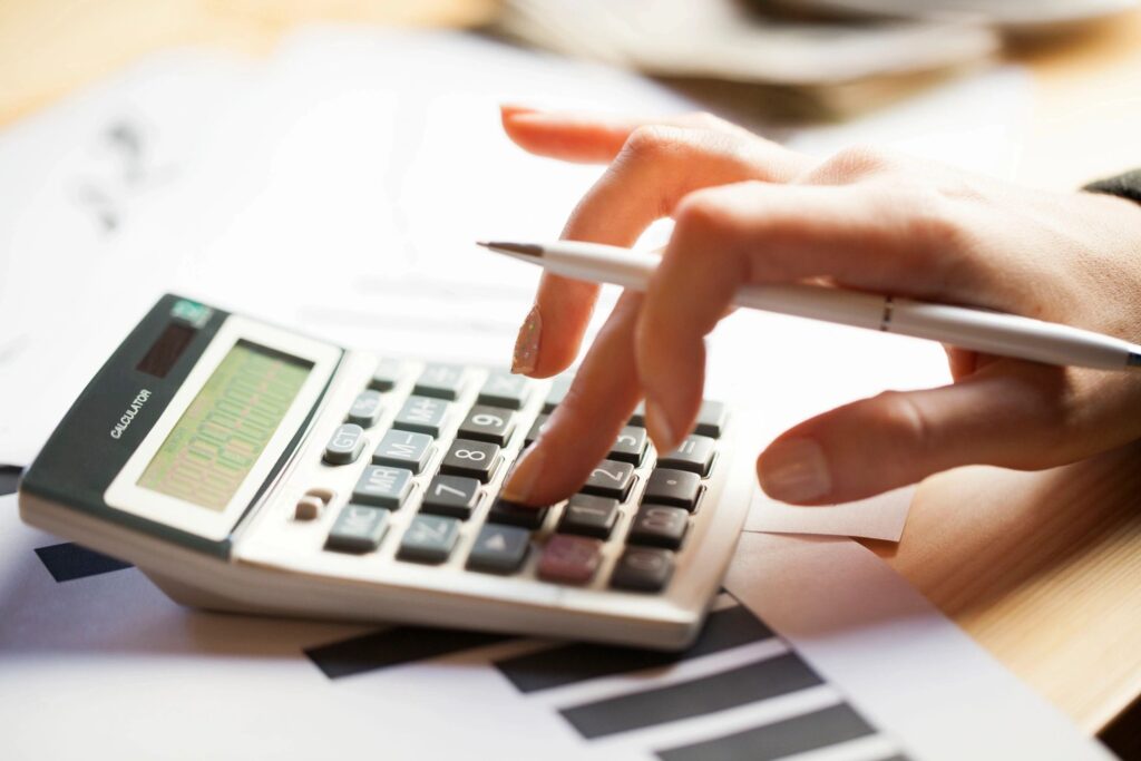 A person using a calculator to calculate the cost of a home.